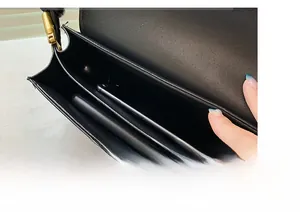 Close-up of black leather baguette bag interior with dual compartments and gold hardware