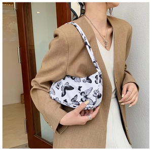 Close-up of stylish canvas underarm bag with butterfly print shown on a model