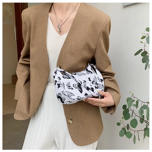 Detail of canvas crescent bag with black butterfly print worn with a brown blazer