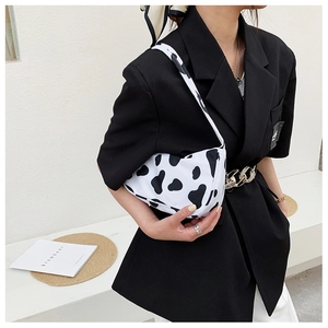 Side view of cow print canvas shoulder bag styled with a minimalist black blazer