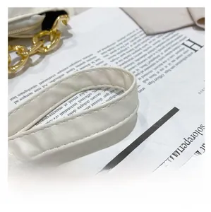 Detail of cream white leather shoulder strap with elegant gold chunky chain and stitching