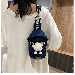 Close-up of denim crossbody bag featuring a cute white plush lamb and lettered strap