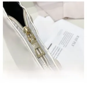 Close-up of smooth gold metal zipper and white pleated leather texture on shoulder bag