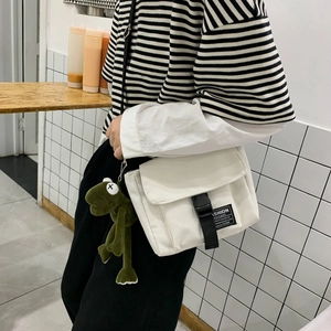 Japanese style white canvas messenger bag with a green frog charm and black buckle