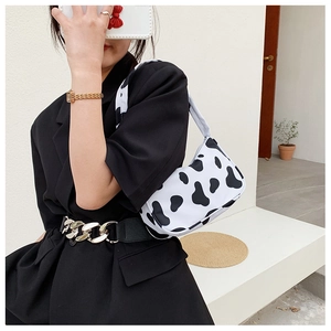 Detail of trendy cow print underarm bag with black and white patterns on leather