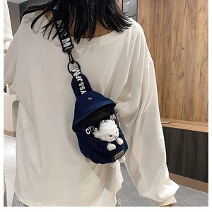 Detail of dark blue denim crossbody bag featuring custom YS&JPM strap and plush charm