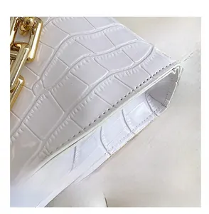 Detailed macro view of white crocodile pattern leather and thick gold chain link