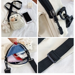 Detail of off-white canvas crossbody bag showing metal zipper and cute bear charms