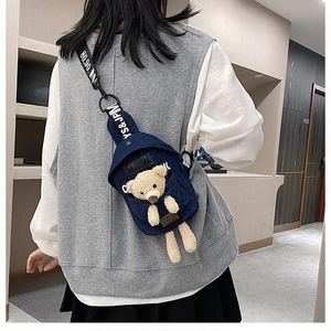 Detail of blue denim crossbody bag featuring a cute 3D teddy bear plush decoration