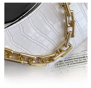 Close-up of white crocodile pattern leather handbag with chunky gold chain detail