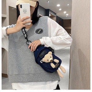 Detail of cute teddy bear ornament and printed strap on blue denim crossbody chest bag