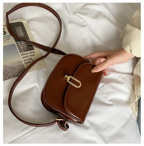 Details einer braunen Vintage-Satteltasche mit Goldverschluss und glatter Textur