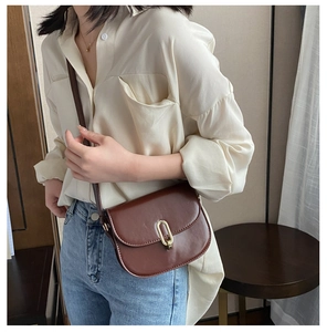 Nahaufnahme einer braunen Satteltasche mit goldener U-Schnalle an einem Modell