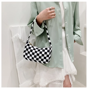 Detail of checkered shoulder bag with gold zipper shown on model in green shirt