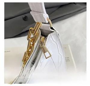 Detail view of white crocodile pattern handbag with chunky gold chain and smooth zipper