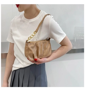 Detail of khaki pleated shoulder bag with elegant leather and gold chain strap on model