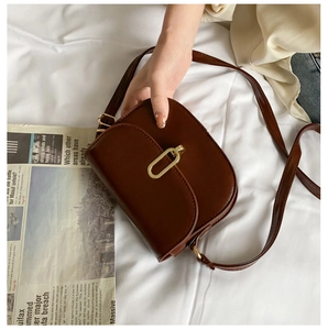Flachbild von Vintage dunkelbrauner Satteltasche mit goldener Schnalle und Zeitung
