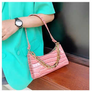 Close-up of pink crocodile pattern baguette bag with stylish gold chunky chain detail