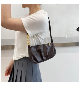 Macro detail of brown pleated leather shoulder bag with gold chain and black strap
