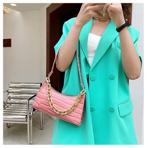 Close-up of pink crocodile pattern underarm bag featuring a chunky gold chain strap