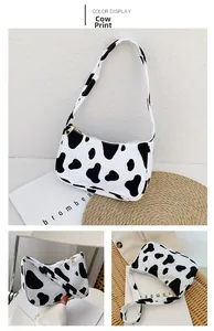 Detail view of stylish cow print underarm bag with contrast colors and gold zipper
