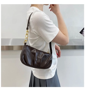 Brown pleated leather hobo bag with gold chain strap shown on a female model