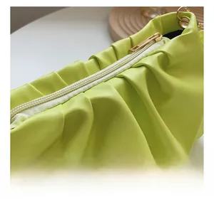 Close-up of smooth gold zipper and vibrant lime green pleated texture on cloud bag
