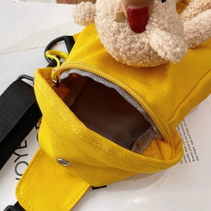 Bright yellow canvas crossbody bag featuring a cute plush bear ornament and black strap