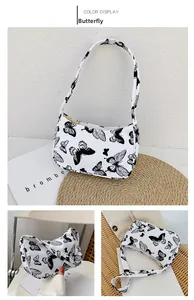 Detail view of canvas shoulder bag with black butterfly print and gold zipper closure