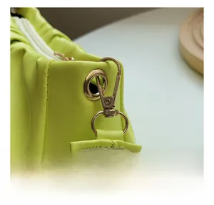 Close-up of golden metal swivel hook and textured leather stitching on lime cloud bag