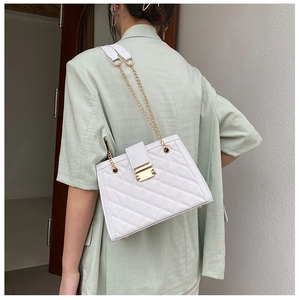 Dettaglio della borsa a tracolla trapuntata bianca indossata su un blazer verde chiaro chic