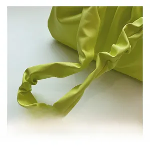 Detailed close-up of the ruffled shoulder strap on the neon green cloud-shaped bag