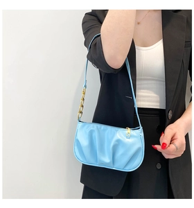 Detail of light blue pleated shoulder bag featuring gold chain and sleek leather strap