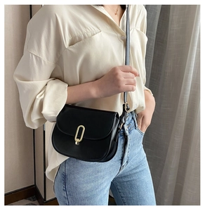 Nahaufnahme der schwarzen PU-Satteltasche mit goldenem Metallverschluss am Outfit