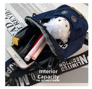 Detail view of denim crossbody bag interior capacity with phone, sunglasses and cosmetics