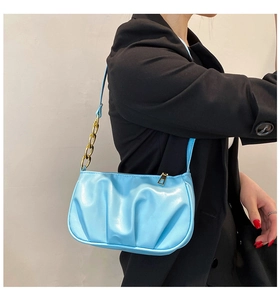 Light blue pleated shoulder bag with gold chain strap detail on black blazer