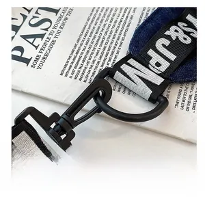Macro shot of black metal swivel hook and jacquard letter strap on denim crossbody bag