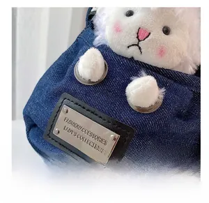 Detail of blue denim bag featuring a cute white plush bear and silver fashion metal plate