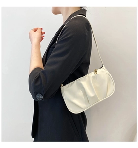 Close-up of pleated beige faux leather shoulder bag with gold zipper and slim strap