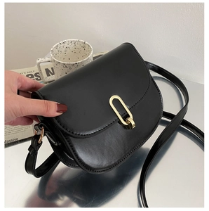 Detail einer minimalistischen schwarzen Satteltasche mit goldener U-Schnalle und Lederstruktur