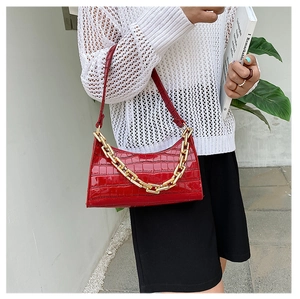 Close-up of red crocodile-pattern underarm bag with thick gold chain decoration