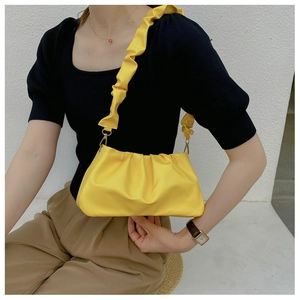 Detail of bright yellow ruched cloud bag featuring a ruffled scrunchie strap and gold clasp