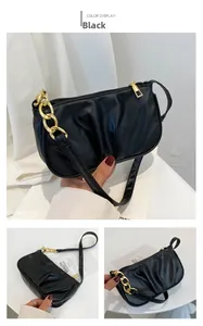 Detail view of black pleated shoulder bag featuring a chunky gold chain and zipper