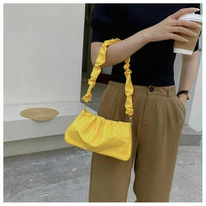 Fashionable bright yellow pleated cloud bag with ruffled strap styled on a model's shoulder