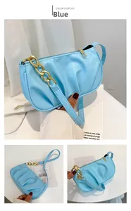 Detail of light blue pleated shoulder bag with gold chain and smooth zipper texture