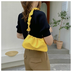 Detail of soft yellow cloud-style shoulder bag with elegant pleated leather texture