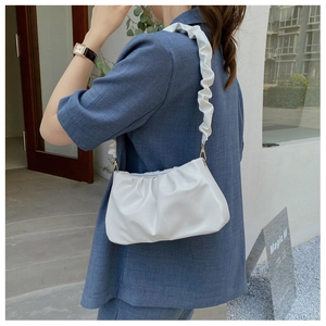 Detail of white pleated cloud bag showing soft faux leather texture and gathered shoulder strap