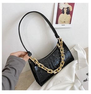Detail of black crocodile texture leather bag with chunky gold chain decoration