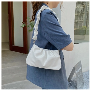 Detail of white pleated cloud bag showing soft leather texture on a shoulder strap