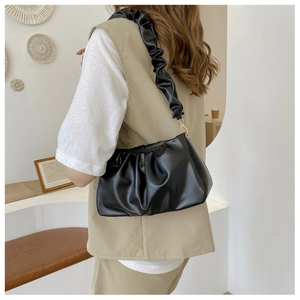 Detail of matte black cloud bag showing soft pleated texture and gold metal buckle
